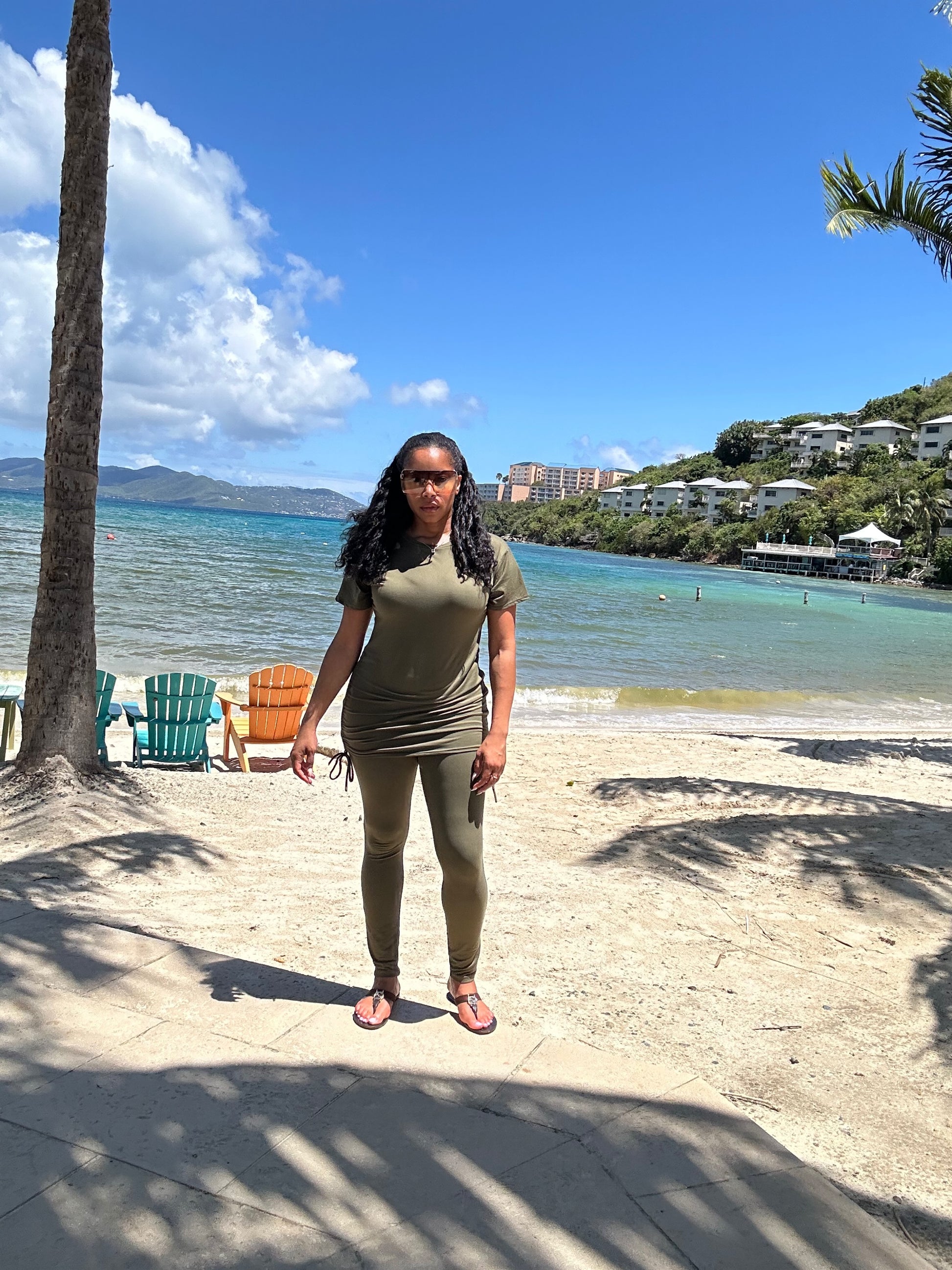 Woman standing on a beach with palm trees and ocean view